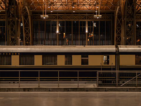 Old train waggon in an illuminated station. Empty platform in a building for public transportation. The ancient steel frame construction of the historical architecture is visible.