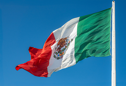 San Jose del Cabo Centro, Mexico - July 16, 2023: Closeup of the flag itself set against blue sky of National Mexican flag