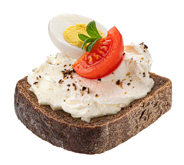 Slice of rye bread with cream cheese, tomato and egg isolated on white background Slice of rustic rye bread with cream cheese, tomato and boiled egg isolated on white background butter margarine isolated portion stock pictures, royalty-free photos & images