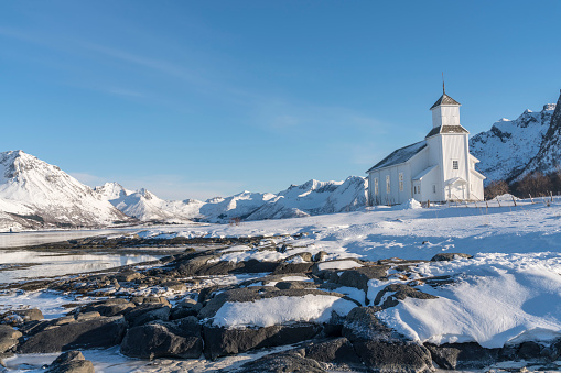 White wooden church at the coast in Gimsøy on Gimsoysand island in Lofoten archipelago in snow.