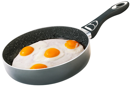 Traditional gourmet breakfast, delicious yummy Sunny side up fried eggs, done in the new, modern designed, heavy duty, non-stick black colored Wok frying pan, with non-slip handle and ceramic coated white spotted inner surface, isolated on white background, side view.