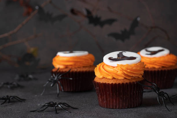 istock Bright sweet cupcakes with crem for Halloween celebration on a brown background with decor 1697247421