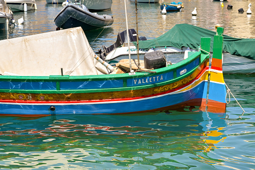 St Julians, Malta - 2 August 2023: Small wooden fishing boat painted in different colours in the harbour near St Julians.