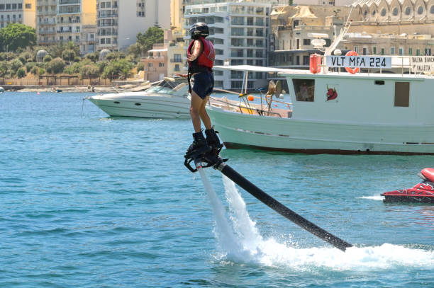 Young person learning to use a flyboard in St Julian's Bay, Malta St Julians, Malta - 2 August 2023: Young person learning to use water jet boots in St Julian's Bay st julians bay stock pictures, royalty-free photos & images