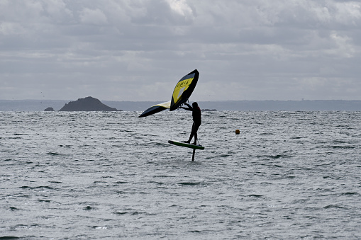 Erquy, Brittany, France, August 27, 2023 - A young athlete on a wing foil board in the harbor area of Erquy, Brittany.