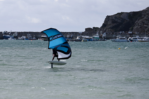 Erquy, Brittany, France, August 27, 2023 - A young athlete on a wing foil board in the harbor area of Erquy, Brittany.