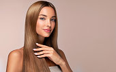 Portrait of woman with perfect long straight hair in a natural color. Hairstyling hair care makeup and manicure.
