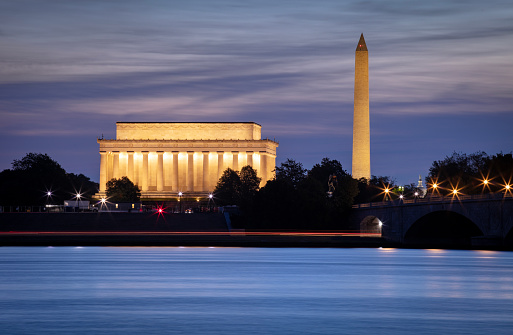 A long exposure of the Lincoln Memorial at Dusk. The monument is crowded with people coming and going. The colorful sky is seen above as the sun is going down.