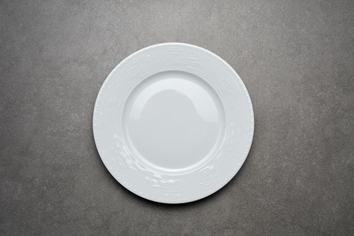 Table top view empty white porcelain plate on the gray ceramics table background