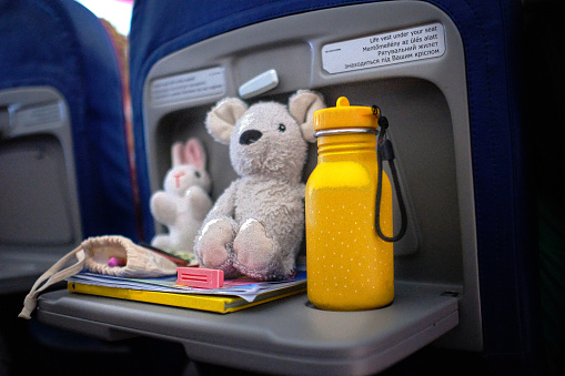 Super cute selection of kids toys displayed on foldable table in the airplane. Travel with kids. Cute mouse, rabbit and drinking bottle close up.