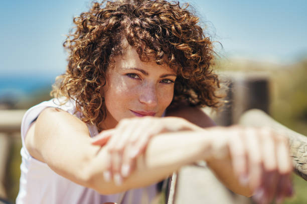 istock Young woman with curly hair and blurred hands 1697414315