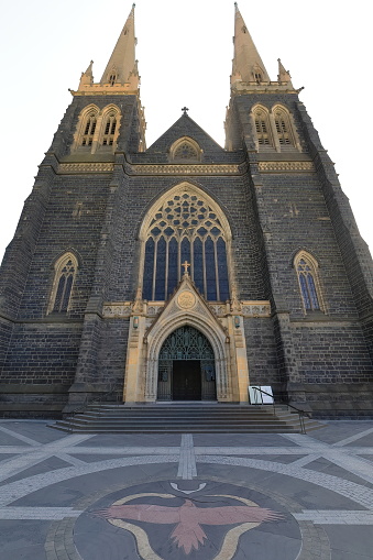 Frontal facade of the AD 1858 founded, AD 1897 consecrated St.Patricks Cathedral built in Gothic revival style with 62 metres tall flanking towers, as seen from its forecourt. Melbourne-VIC-Australia.