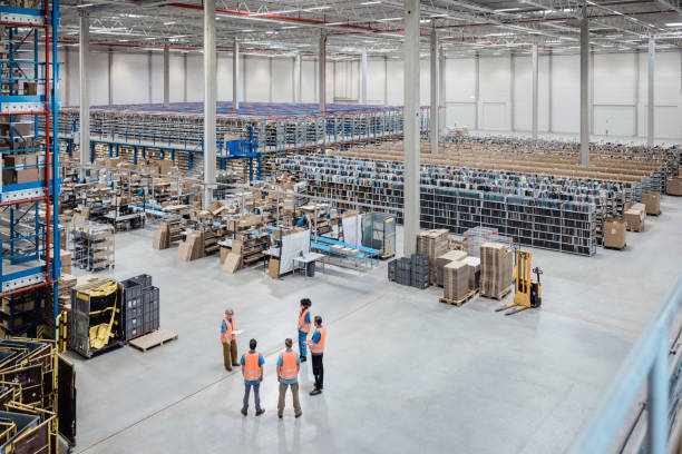 Senior woman discussing work with team of workers in warehouse