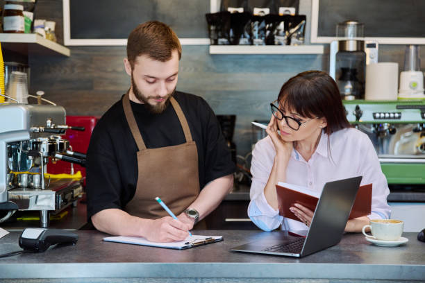 istock Team male and woman talking, working, using laptop, coffee shop 1697465198