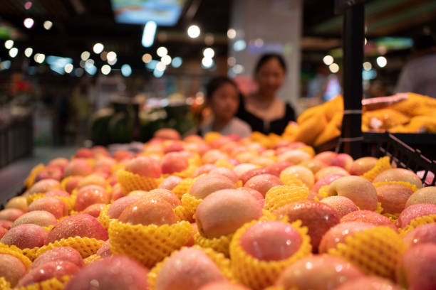 Fresh peaches and nectarines with vibrant red-yellow hues piled together, accented by green leaves and market textures