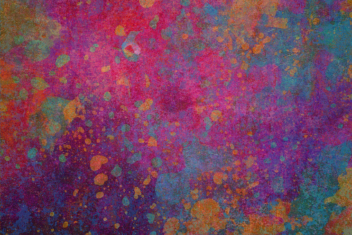 This is an abstract background that bursts with a multitude of colors. The dominant colors are red, purple, orange, and blue. The background has a textured appearance, with splotches and splatters of different colors creating a vibrant and chaotic mood. The overall impression is one of dynamic energy and bold expression.