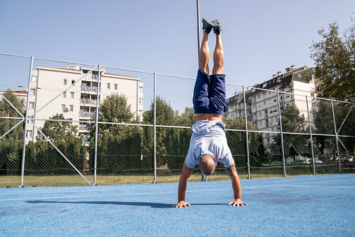 Young athlete doing handstand while exercising outdoors