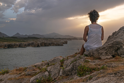 Asturias, Spain. 08/22/2023. Woman contemplating the sunset. Asturian Eastern Coast