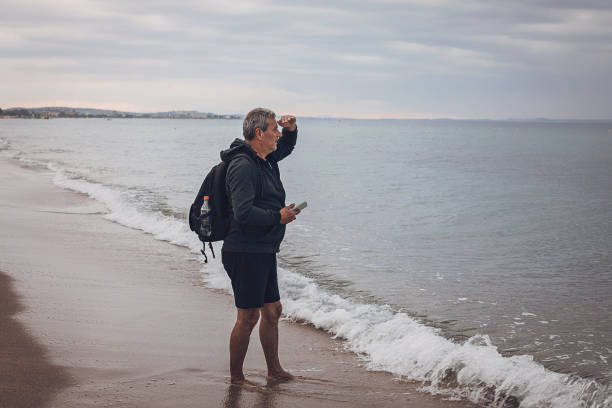 istock A man walks along a sandy seashore and uses a mobile phone 1697617796
