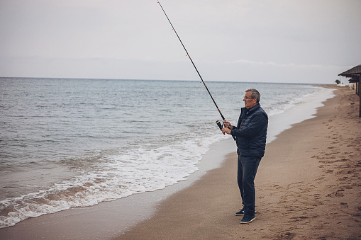 An elderly man is fishing with a fishing rod