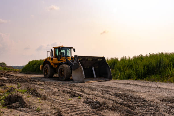 bulldozer giallo - parcheggiato su strada sterrata - zona rurale con campo e alberi - earth mover working field dirt foto e immagini stock