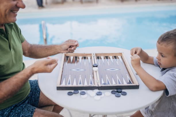 istock Grandfather and grandson play backgammon 1697631820