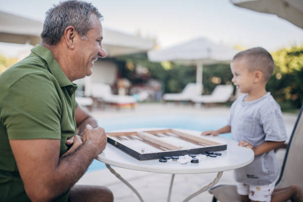 istock Grandfather and grandson play backgammon 1697632218