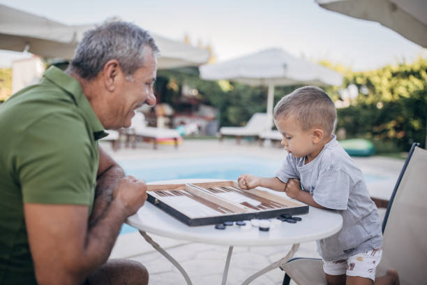 istock Grandfather and grandson play backgammon 1697632219