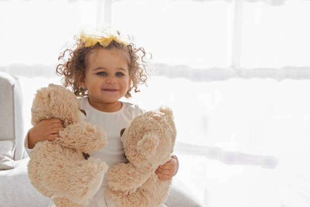 Cute little girl playing with teddy bears in the living room