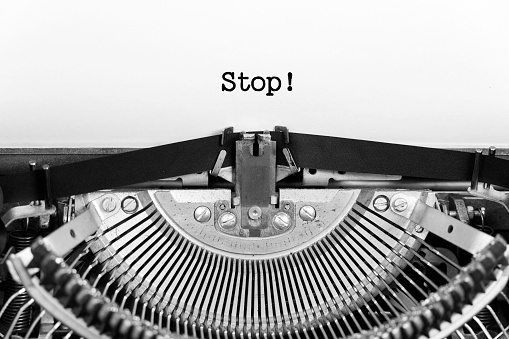 Stop word closeup being typing and centered on a sheet of paper on old vintage typewriter mechanical.