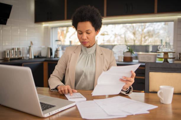 istock Mature woman using calculator while going through bills and home finances 1697802816