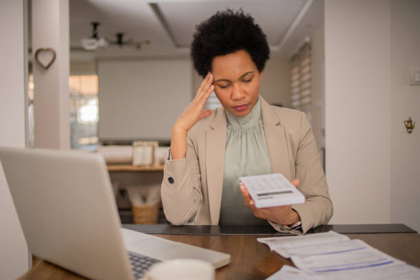 istock Mature woman using calculator while going through bills and home finances 1697802823