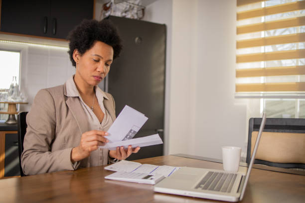 istock Mature woman using calculator while going through bills and home finances 1697802824