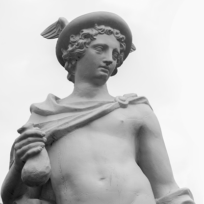 Ancient statue of the antique god of commerce, merchants and travelers Hermes (Mercury). He is olympic gods messenger with wings on his feet and helmet. Black and white image.
