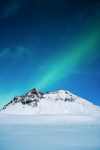 Aurora Borealis. Northern lights and clear skies. Nature. Scandinavian countries. Snow and ice on the mountains. Landscape in winter time. Photo for background and wallpaper.