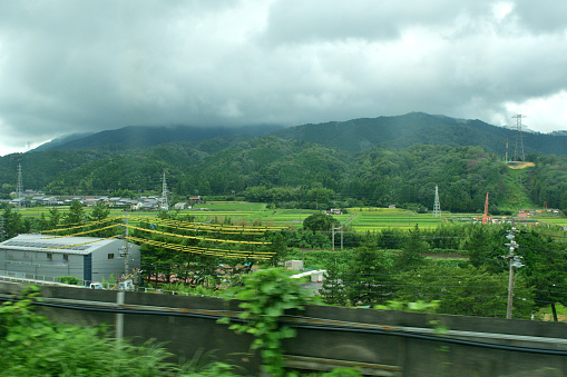 Rural landscape of Japan, taken in late August from Tokaido Shinkansen Super Express in Gifu and Shiga Prefectures before reaching Kyoto from Nagoya.\nGreen farms are rice paddy farms, waiting for harvest in late September or  October.
