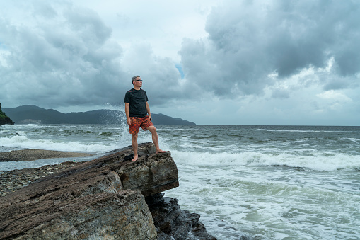 Man standing barefoot on a rock strata by the sea, Tung Ping Chau Marine Park, Hong Kong.