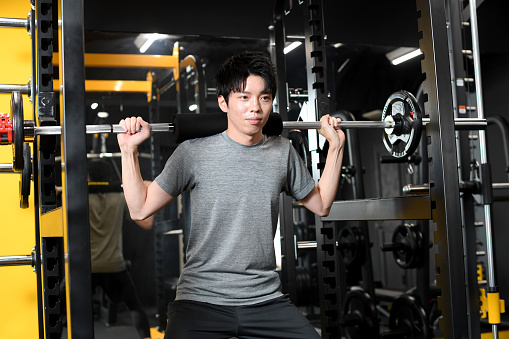 Young Asian young man carrying a barbell at the gym