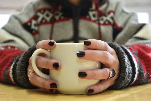 istock Woman's hands in knitted sweater holding coffee cup 1698124164