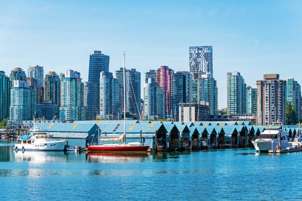 Yacht club with roofed construction for ships seen from Seawall of Stanley Park with downtown skyline, Vancouver, Canada.