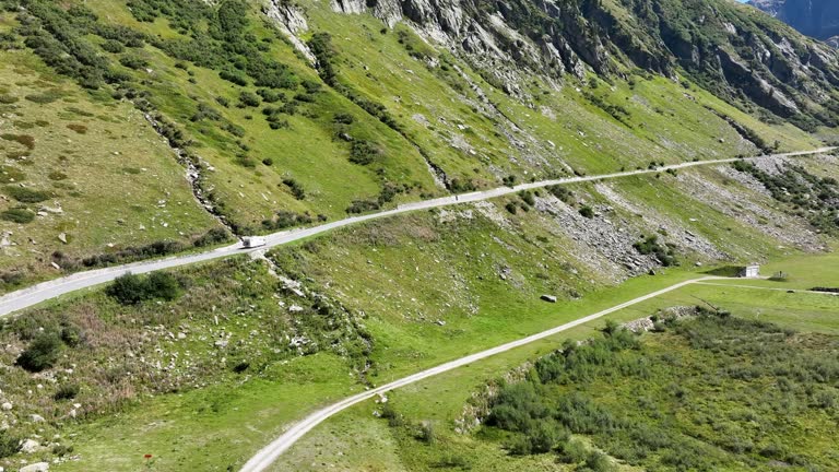 RV camper driving along the Nufenen Pass winding through a beautiful valley in Europe