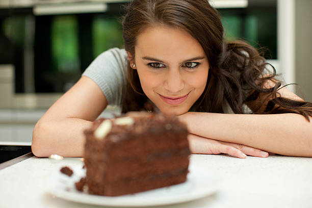 femme regardant sur gâteau au chocolat - petite faiblesse photos et images de collection