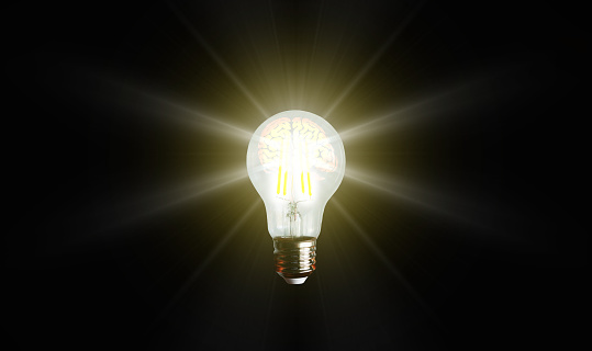 An illuminated or glowing lightbulb on a dark background represents new ideas, innovation, creativity, understanding, knowledge, and inspiration.