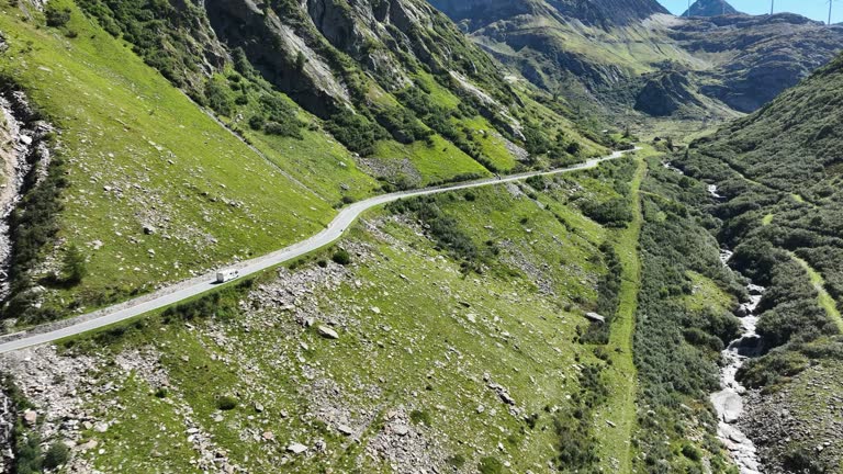 RV camper driving along the Nufenen Pass winding through a beautiful valley in Europe