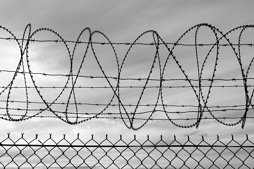 Barbed wire, razor wire and mesh wire fencing at Gate 13 of Sydney Kingsford-Smith Airport.  This image was taken from near Shep's Mound, Ross Smith Avenue, Mascot on a sunny, cold and windy afternoon at sunset on 23 September 2023.