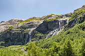 View of the valley of Sofia waterfalls with green mountain slopes, rocks and waterfalls