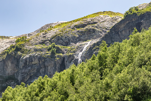 View of the valley of the Sofia waterfalls with green mountain slopes, rocks and waterfalls