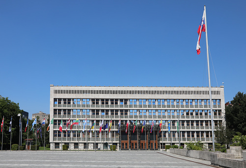 Ljubljana, L, Slovenia - August 15, 2023: Slovenian Parliament Building of the European capital and the large waving flag