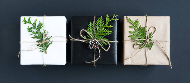 istock Three craft gift boxes with twigs of cedar and rope on dark background. Top view. 1698253151