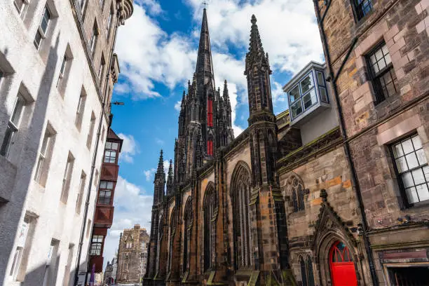 Cathedral with high tower and historic buildings on Castlehill Avenue in Edinburgh, Scotland.